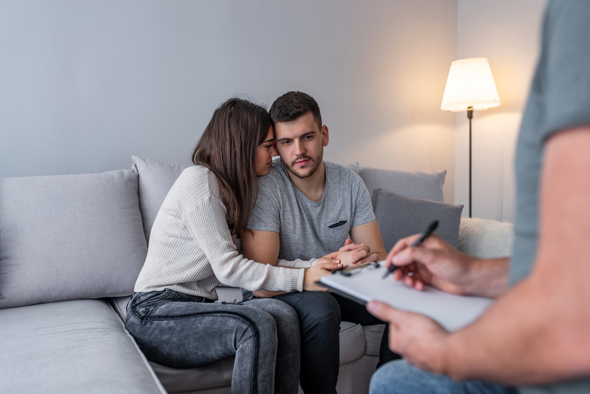 Young couple with psychologist family therapy hugging